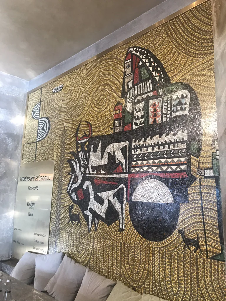 The background of Eren Eyüboğlu’s mosaic panel at IMÇ and Bedri Rahmi’s “Ox Cart” panel at Tatlıcılar Bazaar is made of golden mosaic stones. However, the Betebe glass mosaic factory, established in Turkey in the 1950s, has been unable to produce the ideal bright carmine red and gold mosaic.