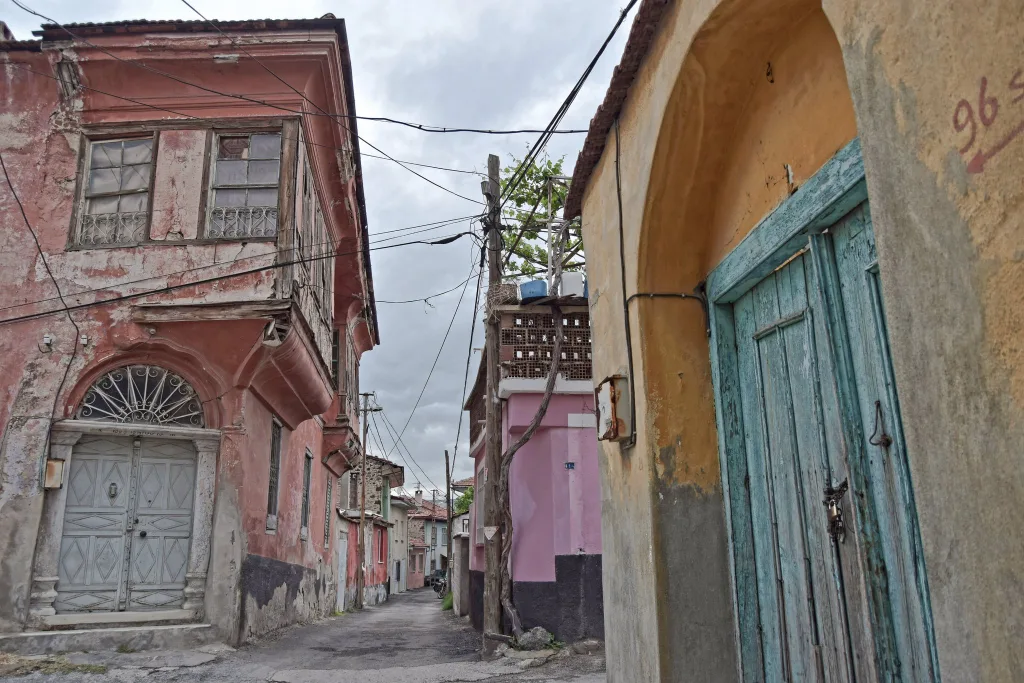 Colors of Turkish houses from Kula. On the left corner, a red house painted with oil-free üstübeç (white color) mixed with iron oxide yellow; on the right, a wall in iron oxide yellow, and a green door obtained by mixing laundry indigo blue with iron oxide yellow.